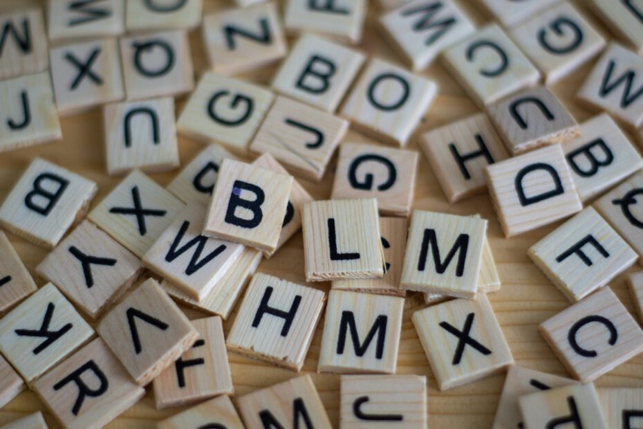 Kleine Holzplättchen mit unterschiedlichen Buchstaben liegen kreuz und quer neben- und übereinander.